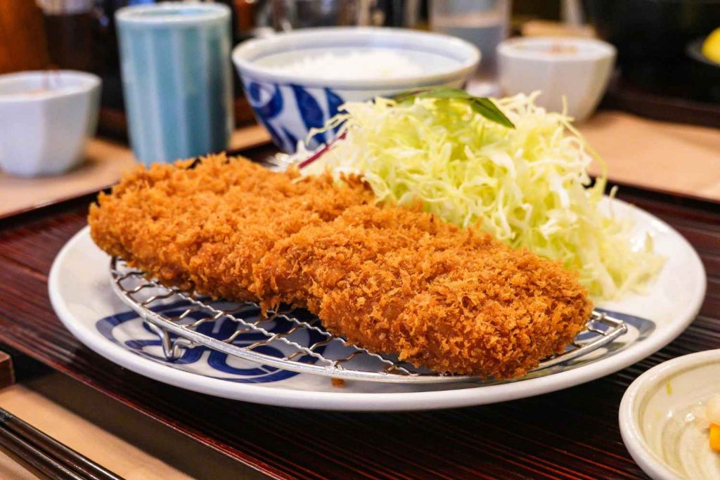 Tonkatsu, prato japonês quente e frito Tonkatsu, prato japonês quente e frito, servido com repolho ralado e arroz.