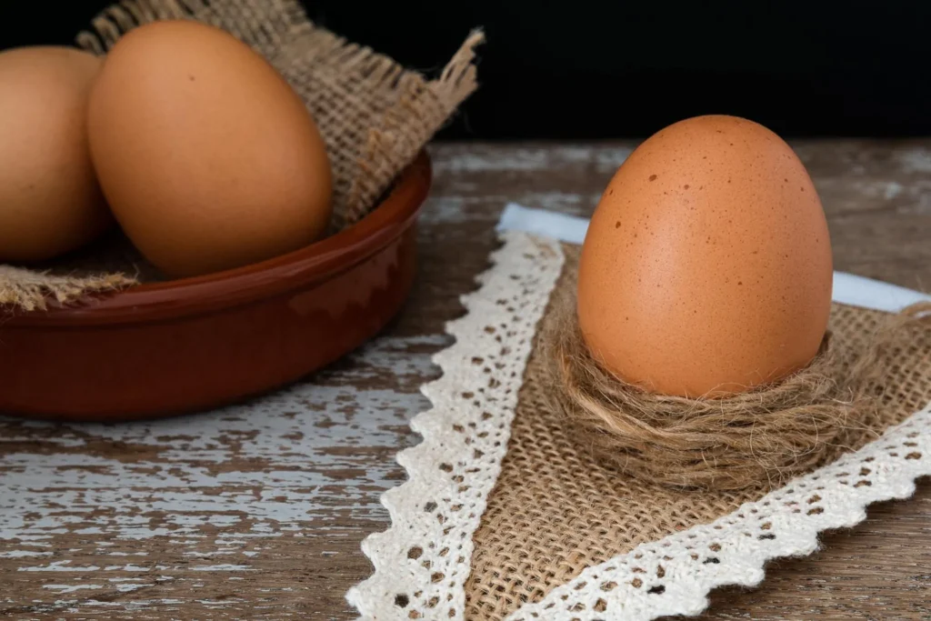 Tipos de ovos: caipira Ovo caipira sobre tecido rústico ao lado de tigela com ovos, representando tipos de ovos e suas variações