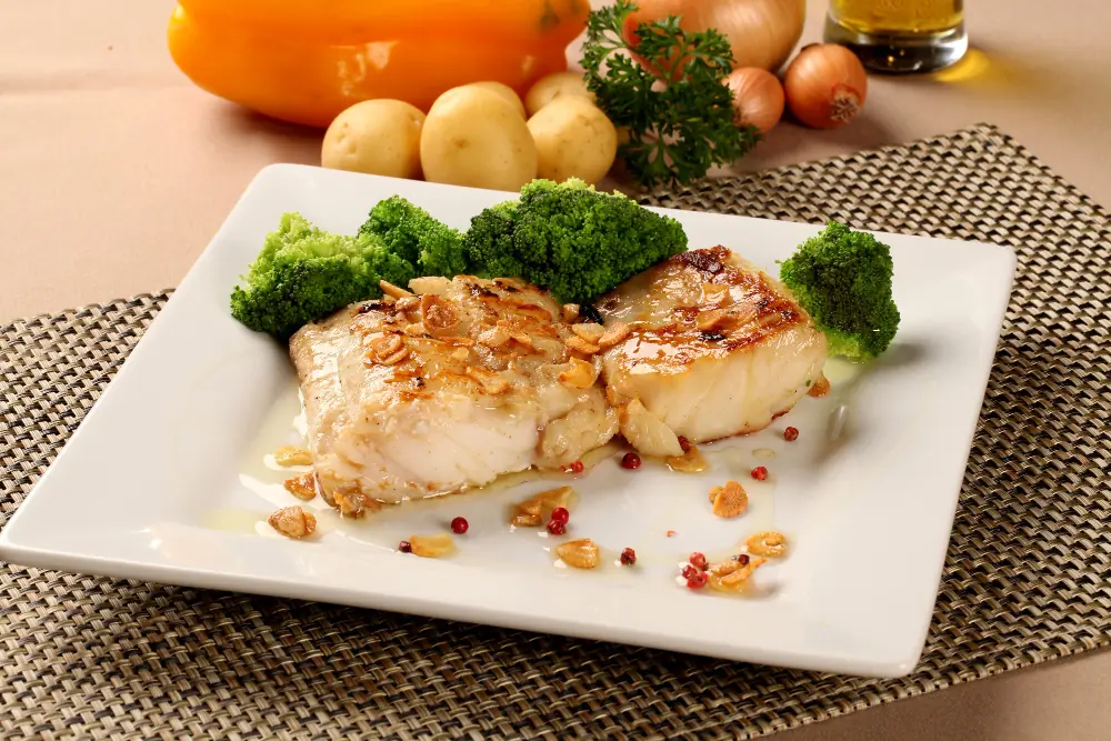 Postas dessalgadas e preparadas Postas de bacalhau servidas com legumes, ilustrando o resultado correto do processo de dessalgar bacalhau.