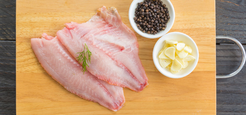 Tipos de peixe: variedades, características e melhores técnicas de preparo 1 Filé de peixe e temperos numa tábua de madeira.