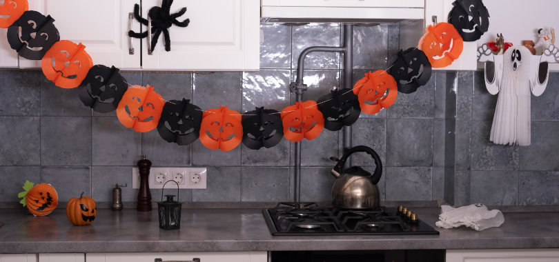 Ideias de decoração de Halloween: inspire clientes e transforme seu estabelecimento 1 Varal de abóboras de Halloween na parede da cozinha sobre o fogão.