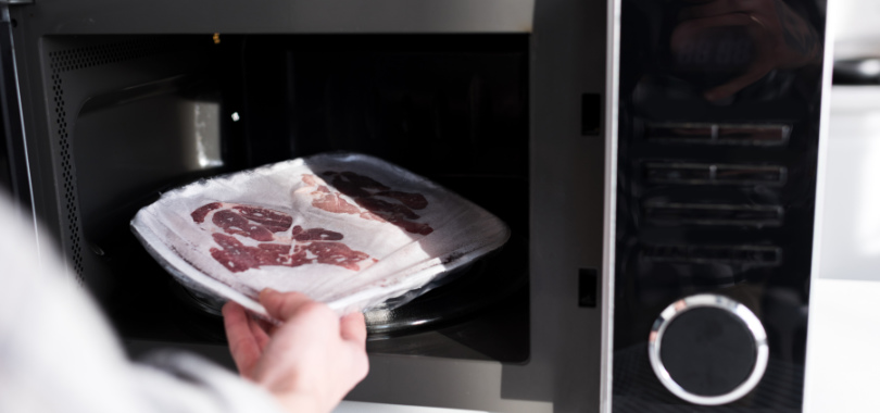 Como descongelar carne rápido e com segurança para manter qualidade e sabor? 1 Mão colando carne para descongelar.